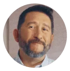 Smiling man with short dark hair and a beard, wearing a light-colored shirt, framed in a circular coral background. Represents trust, experience, and Noom’s supportive member community.